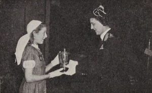 A female Cadet stands on the left. Opposite her, a woman is handing her a silver trophy.