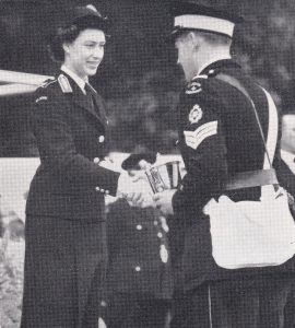 A young man receives a silver trophy and shakes the hand of Princess Margaret.