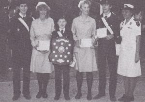 Six Cadets line up for a photograph. The Cadet on the far right is from South Australia, and wears a white Cadet uniform. The remaining five Cadets are from England, and are dressed in their Cadet uniform and are holding awards for winning a competition at the Championships.