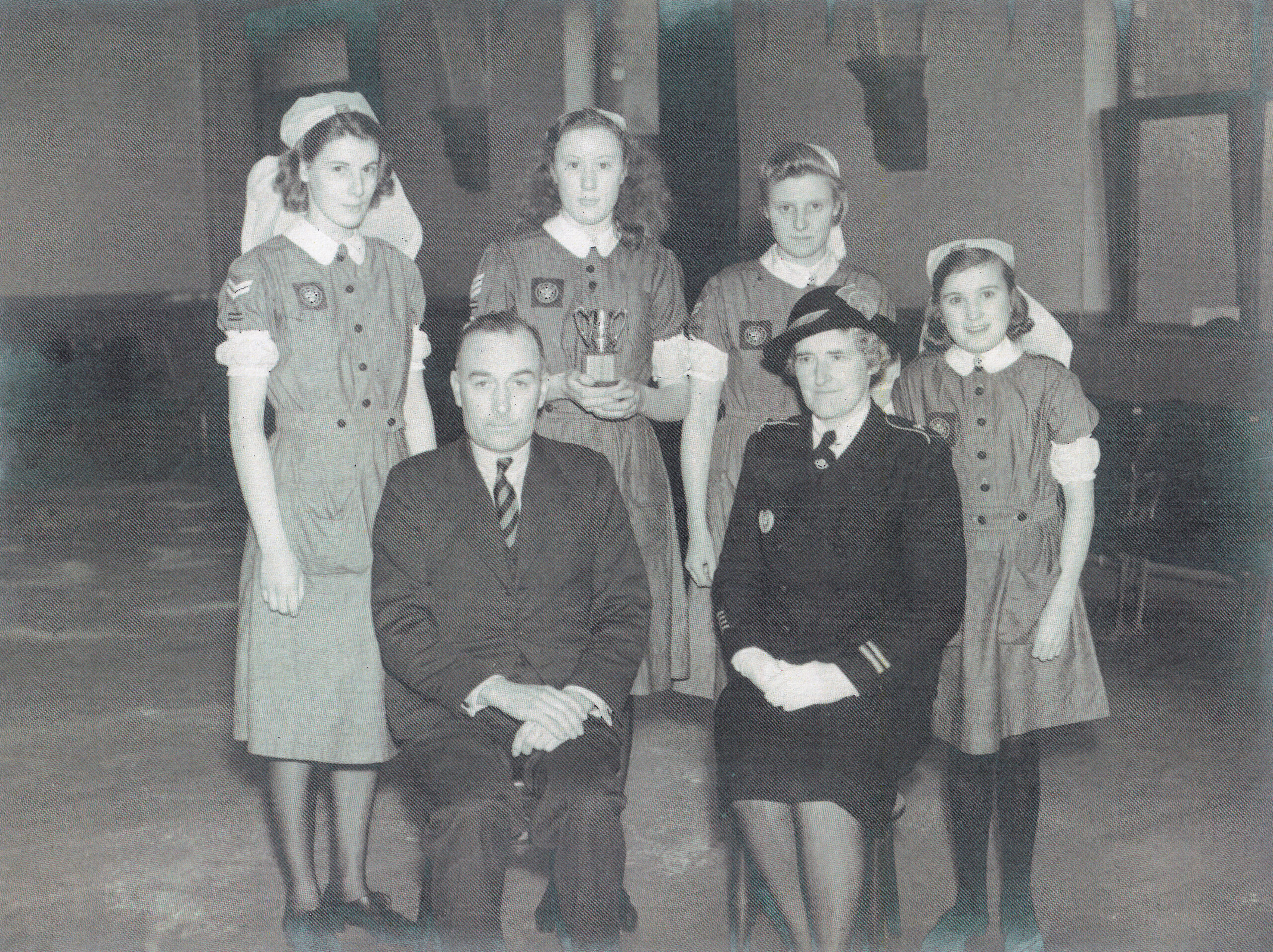 Black and white photograph of four female Cadets standing in a room behind two adults