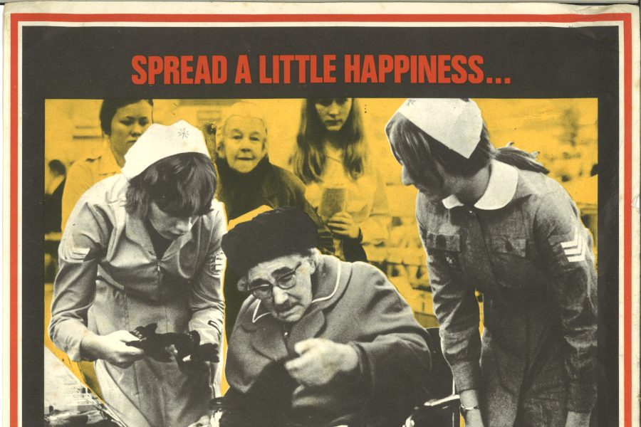 Colour photograph of a poster advertising the Cadets. Features a black and white photograph of two female Cadets assisting an elderly lady in a wheelchair with her shopping.