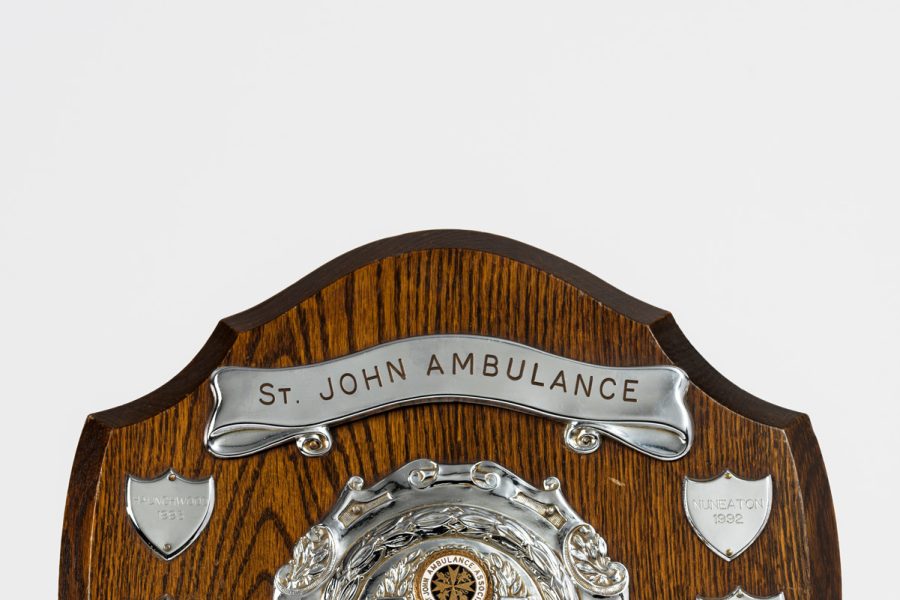 Wooden shield with silver plaques listing winners of bedmaking competition